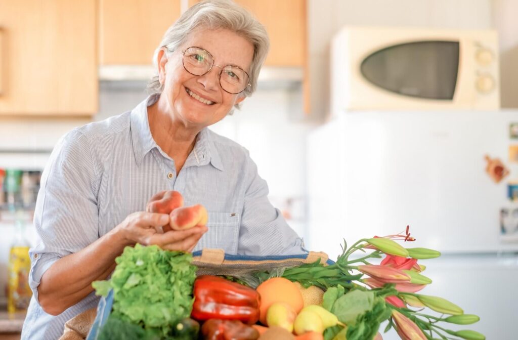 Two older adults preparing fresh vegetables together in a kitchen surrounded by leafy greens tomatoes and seasonal produce
