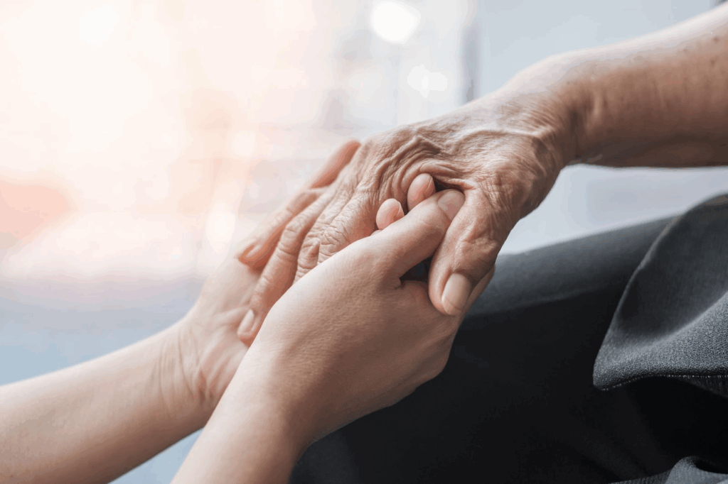 Caregiver holding seniors hand, close up.